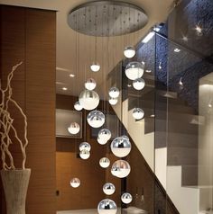 a modern staircase with glass balls hanging from it's sides and a plant in the middle