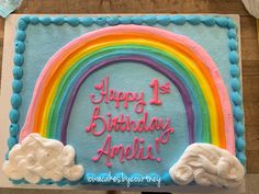 a birthday cake with a rainbow and clouds on it