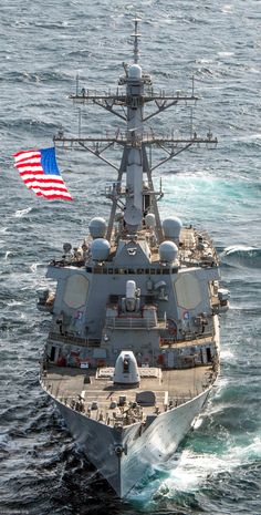 an american flag is flying on the back of a navy ship in the middle of the ocean