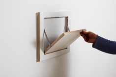 a person holding an open folder in front of a white wall with a window on it