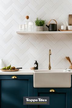 a kitchen with blue cabinets and white tile backsplashing, gold faucets