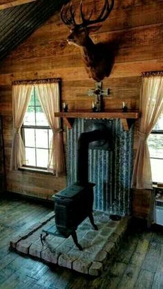 an old fashioned stove in a rustic cabin with deer heads on the wall and windows