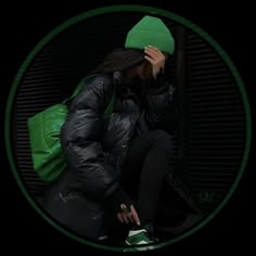 a woman sitting on the ground with her head in her hands and wearing a green hat