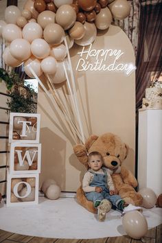 a teddy bear sitting on top of a table next to balloons