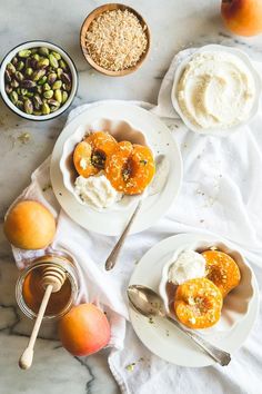 two white plates topped with desserts next to bowls of fruit and nuts on a table