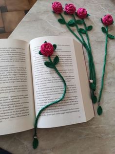 an open book with flowers on it and some beads in the shape of roses next to it