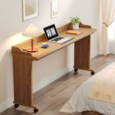 a laptop computer sitting on top of a wooden desk next to a lamp and bed