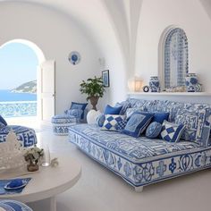 a blue and white living room with an arched doorway leading to the ocean in front of it