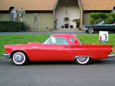 an old red car parked in front of a house