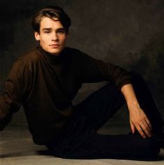 a young man sitting on the ground with his legs crossed