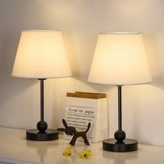 two lamps sitting on top of a white table next to a brown box with yellow flowers