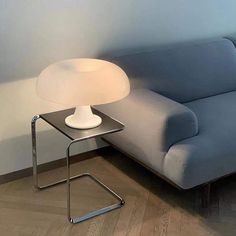 a blue couch sitting next to a table with a white lamp on top of it