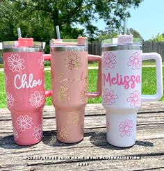 three personalized travel mugs sitting on a picnic table with the name meligo