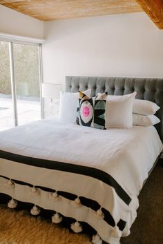 a bed with white sheets and pillows in a bedroom next to a sliding glass door