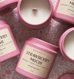 several pink candles sitting next to each other on top of a table with the words strawberry mochi written on them