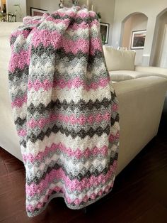 a pink and gray blanket sitting on top of a white couch in a living room