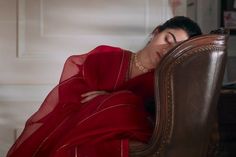 a woman in a red dress is sitting on a brown chair with her eyes closed