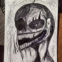 a drawing of a creepy clown with his mouth open and eyes wide open, on a piece of paper