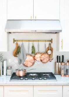 pots and pans are hanging on the wall above the stove