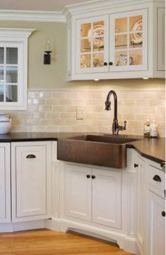 a kitchen with white cabinets and black counter tops, an old fashioned sink is in the center