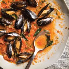 a white plate topped with mussels and sauce