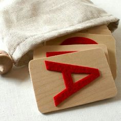 three wooden coasters sitting next to a bag on a white tablecloth with red thread