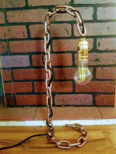 a light bulb is chained to a chain on the floor in front of a brick wall