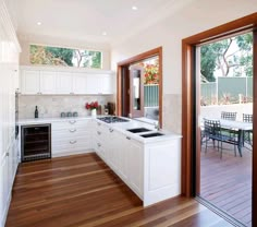 an open kitchen with white cabinets and wood flooring is seen through the sliding glass doors