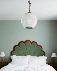 a bed with white sheets and pillows under a light fixture