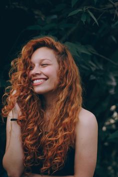 a woman with long red hair smiling at the camera