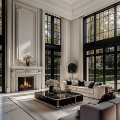 a living room filled with furniture and large windows next to a fire place in the fireplace