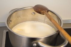 a wooden spoon in a saucepan on the stove with water and milk being stirred