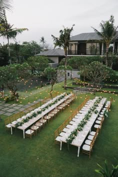 a long table set up with white linens and greenery for an outdoor wedding