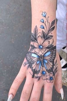 a woman's hand with a blue butterfly tattoo on it and flowers around the wrist