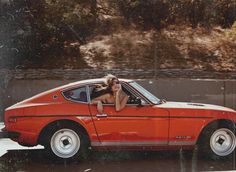 a woman sitting in the drivers seat of an orange car