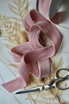 a pair of scissors next to a pink ribbon