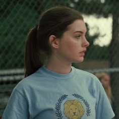 a young woman standing in front of a chain link fence wearing a lion t - shirt