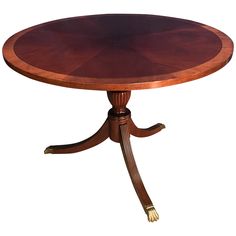 a round wooden table with four legs and a circular top on an oval pedestal base