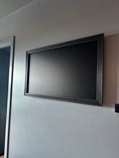 a flat screen tv mounted to the side of a wall next to a door in a room