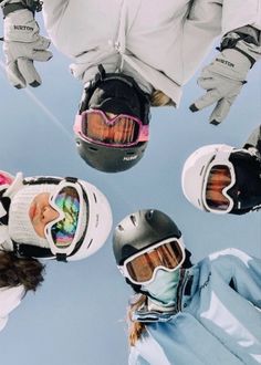 four people wearing skis and goggles standing in a circle