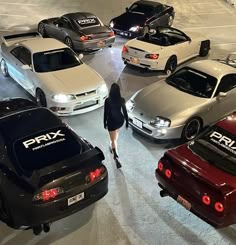 a woman walking through a parking lot next to several parked cars in rows on the pavement