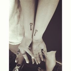 two people holding hands with tattoos on their arms and the other hand has a key tattoo on it