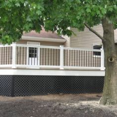 a large tree in front of a house with white railings and balconies