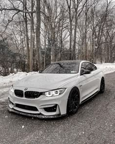 a white car is parked on the side of the road in front of some trees