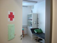 a hospital room with a red cross sign on the wall and a black bench in front of it