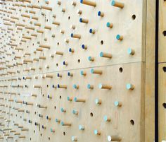 a wooden wall with several holes and pegs attached to the side, all lined up against each other