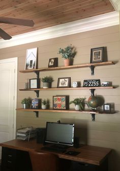 a desk with a laptop computer on top of it next to shelves filled with pictures