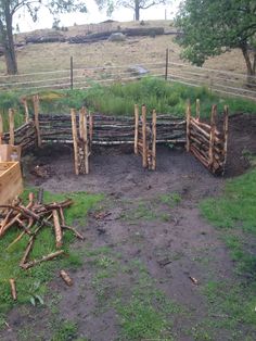 a fence made out of sticks and logs in the middle of a field with grass