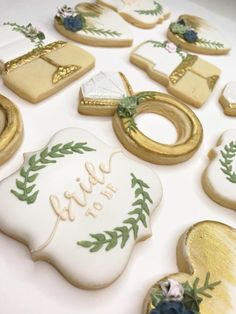 decorated cookies are arranged in the shape of wedding rings and wreaths on a table