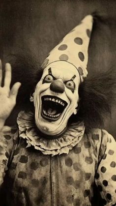 an old photo of a creepy clown with his hands in the air